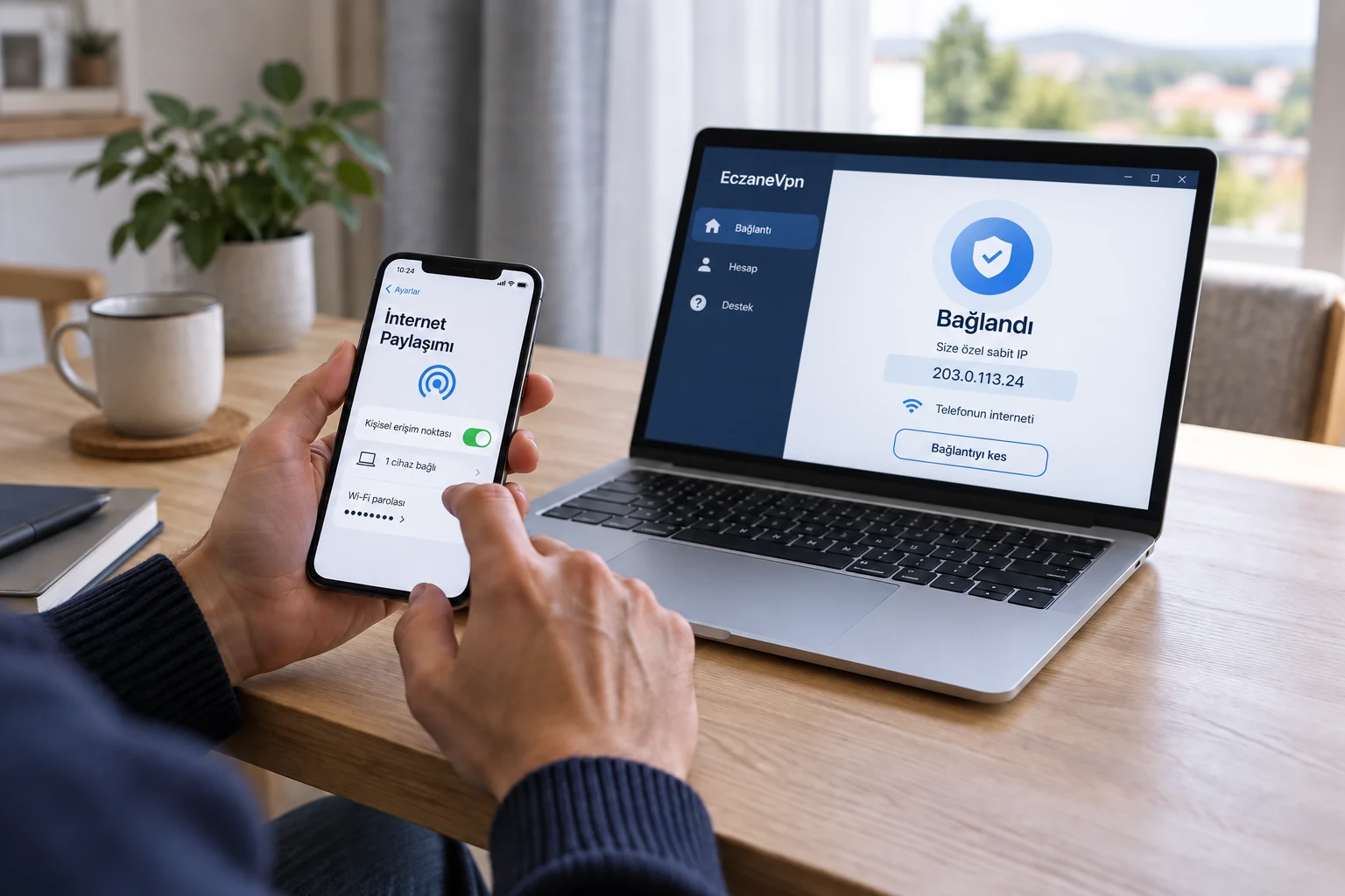 Dizüstü bilgisayarının yanında telefondan internet paylaşımını açan kişi